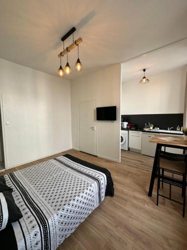 Cet appartement comprend une chambre avec un lit et une table ainsi qu'une cuisine. dans l'établissement Le Mirabelle, à Saintes