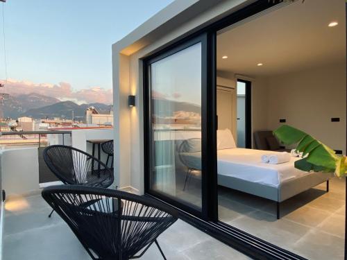 Habitación con balcón con cama y sillas. en Hyperion Penthouse, en Patra