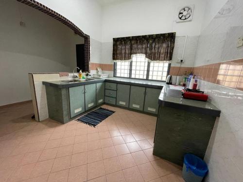 uma cozinha com armários verdes e piso em azulejo em My Delima Home for MusIim em Keluang