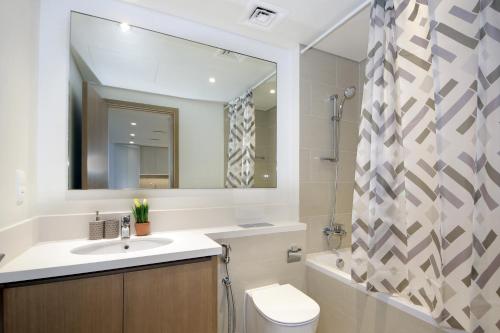 a bathroom with a sink and a toilet and a mirror at Elegant Waterfront 1BHK in Dubai Creek Harbour in Dubai