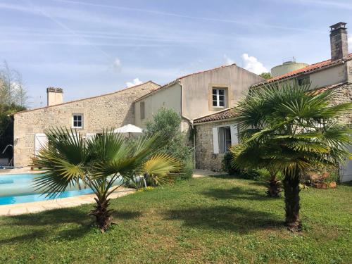 une maison avec deux palmiers devant elle dans l'établissement Maison ancienne avec piscine au milieu des vignes, à Marignac
