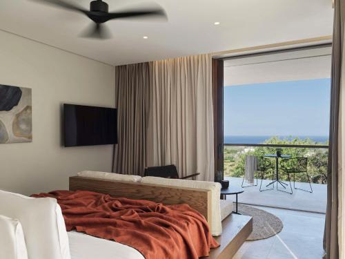 Schlafzimmer mit einem Bett und Blick auf einen Balkon in der Unterkunft Magma Resort Santorini, In The Unbound Collection By Hyatt in Vourvoúlos