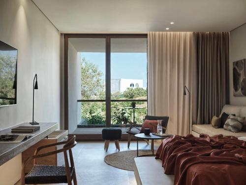 a bedroom with a bed and a large window at Magma Resort Santorini, In The Unbound Collection By Hyatt in Vourvoúlos