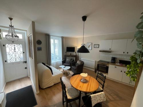 a living room with a table and a kitchen at Sisley Cottage in Moret-sur-Loing