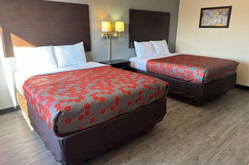 a hotel room with two beds and a ottoman at Econo Lodge in Waite Park