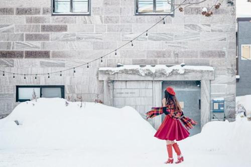 a girl in a red dress standing in the snow at 石と鉄-House of STONE and IRON in Otaru