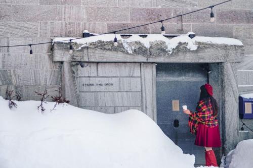 a woman standing in front of a door in the snow at 石と鉄-House of STONE and IRON in Otaru