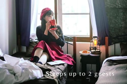 a woman sitting on a bed holding a cup at 石と鉄-House of STONE and IRON in Otaru