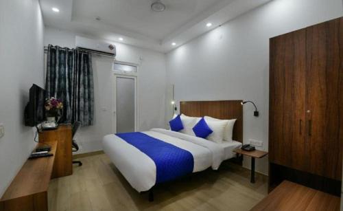 a bedroom with a large bed with blue pillows at Hotel The Emporio A Corporate Suites in Ghaziabad
