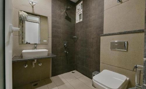 a bathroom with a sink and a toilet and a mirror at Hotel The Emporio A Corporate Suites in Ghaziabad