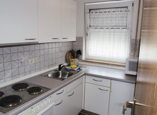eine Küche mit weißen Schränken, einem Waschbecken und einem Fenster in der Unterkunft FÜRTH/NÜRNBERG Monteurwohnung in Fürth
