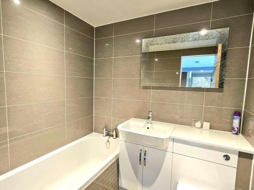 a bathroom with a sink and a tub and a mirror at Lovely 3 bedroom Apartment By Sensational Stay Short Lets & Service Accommodation with 6 beds in Edinburgh