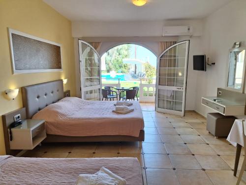 アギア・マリーナ・ネア・キドニアスにあるPerla Beachのベッド2台、テーブルと椅子が備わるホテルルームです。