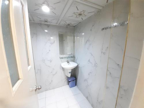 La salle de bains blanche est pourvue d'un lavabo et d'une douche. dans l'établissement OYO 1226 Hoang Gia Hotel, à Hô-Chi-Minh-Ville