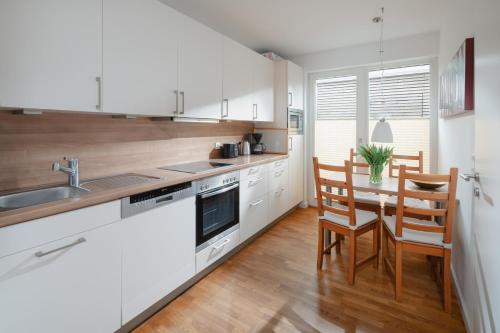 a kitchen with white cabinets and a table with chairs at Ferienhaus Haus an der Mühle in Norderney