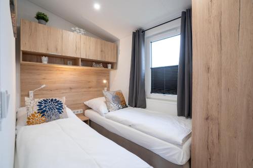 ein kleines Zimmer mit zwei Betten und einem Fenster in der Unterkunft Ostseecamp Ferienhaus "Sonneneck" mit umzäuntem Grundstück in Scharbeutz