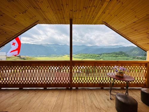 een balkon met een tafel en uitzicht op de bergen bij Guest House MARGALITI-საოჯახო სასტუმრო მარგალიტი in Omalo