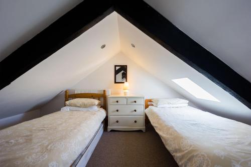 two beds in a attic bedroom with a roof at Pine Cottage Little Haven in Little Haven