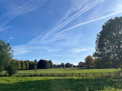 a field with a fence and trees in the sky at Quarry Cottage Courtyard Garden Pass the Keys in Cirencester