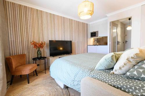 - une chambre avec un lit, une télévision et une chaise dans l'établissement Magnifique Appart Ac Terrasse-Plage à Pied-Parking privé, à Carqueiranne
