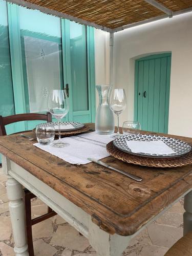 a wooden table with wine glasses and plates on it at Giardino dei Trulli Cummerse in Faccia di Trippa di Monte