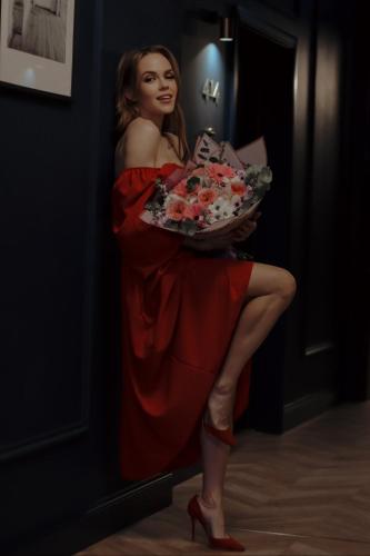 a woman in a red dress holding a bouquet of flowers at Aparthotel Amella in Rīga