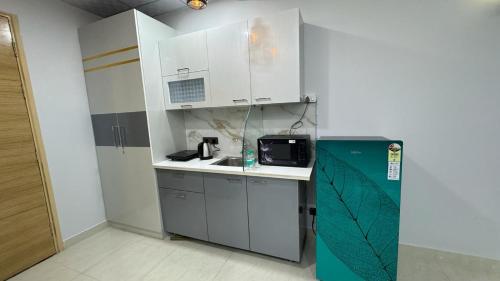 uma cozinha com armários brancos, um lavatório e um frigorífico em Exotic studio em Ghaziabad