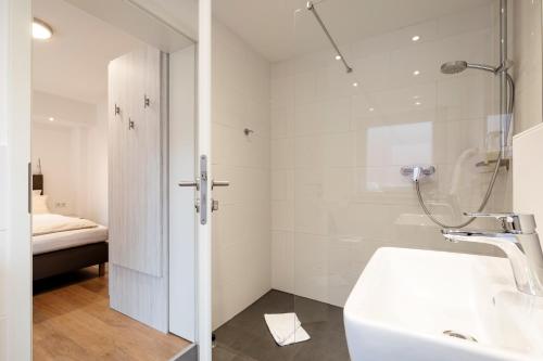 a white bathroom with a shower and a sink at Hotel Felsen-Eck in Helgoland