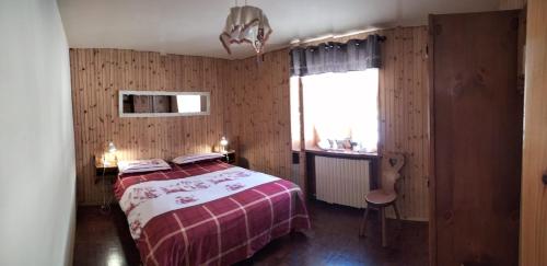 um quarto com uma cama vermelha e branca e uma janela em Appartamentinid em Valtournenche