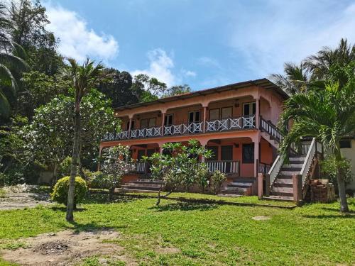 a house with a balcony and palm trees at Matahari Long Beach in Perhentian Islands