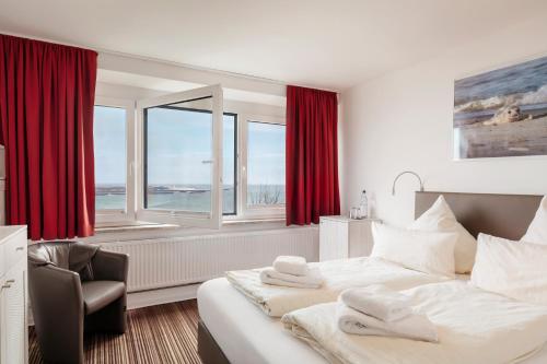 Hotel Felsen-Eck في هيلغولاند: غرفة نوم بسرير وكرسي ونوافذ