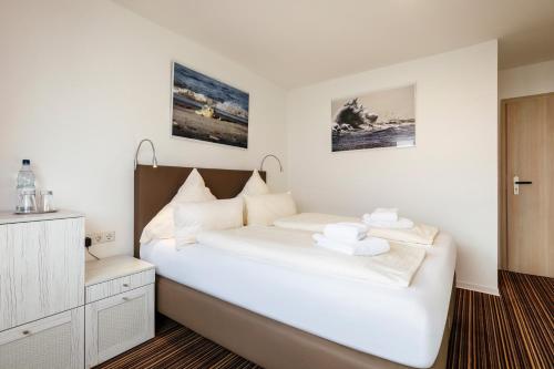 a bedroom with a white bed with towels on it at Hotel Felsen-Eck in Helgoland