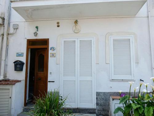 ein weißes Haus mit einer Tür und zwei Fenstern in der Unterkunft Casetta Angela in Ischia