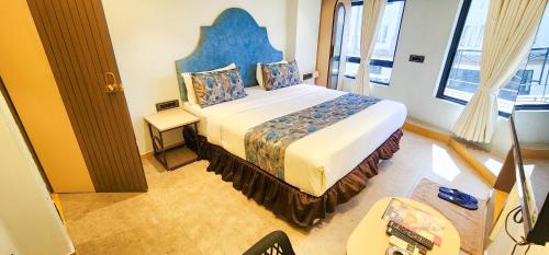 a bedroom with a large bed with a blue headboard at Hotel Nova Bling in Rajkot