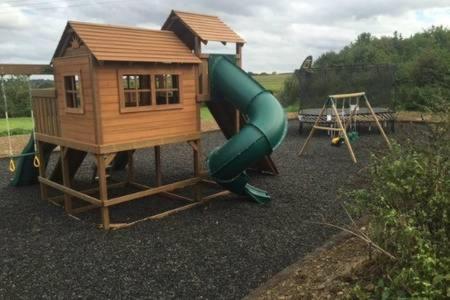 a playground with a house and a slide at Partridge Place at Tove Valley Cottages in Towcester