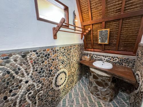 ein Badezimmer mit einem Steinwaschbecken und einem Fenster in der Unterkunft Sumatra Orangutan Treks Villa in Timbanglawang