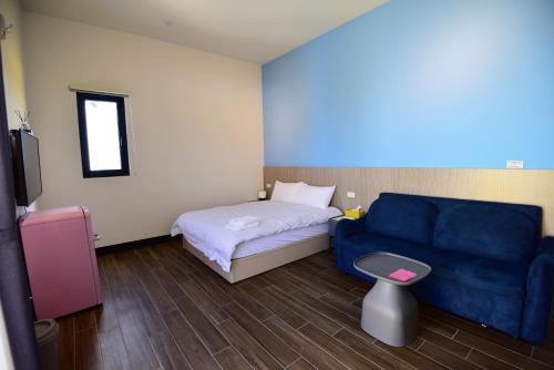 a bedroom with a blue couch and a bed at Diving Duck B&B in Magong