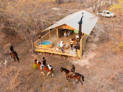 a group of people riding horses in front of a house at AfriCamps Waterberg in Vaalwater