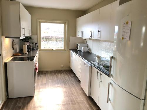 a kitchen with white cabinets and a window at Fish factory -The real Lofoten experience in Ballstad