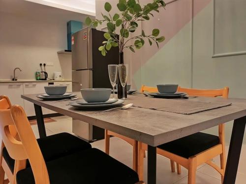 a wooden table with chairs and a kitchen with a refrigerator at Mupify Homestay Gala City Gala Residences A4 in Kuching