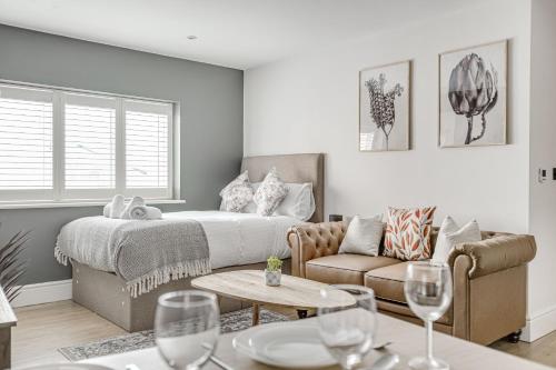 uma sala de estar com uma cama, um sofá e copos de vinho em Modern 1 BR apt near town centre by Tent serviced apartments em Egham