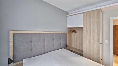 a bedroom with a bed with a headboard and cabinets at HOLIDAY HOME Bel Mare 109b z tarasem i ogródkiem in Międzyzdroje