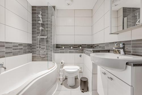 a white bathroom with a tub sink and a toilet at Modern 1 BR apt near town centre by Tent serviced apartments in Egham