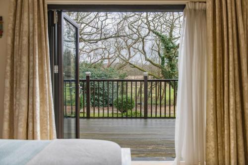 a bedroom with a sliding glass door to a deck at Honeywood Lodge by Bloom Stays in Canterbury