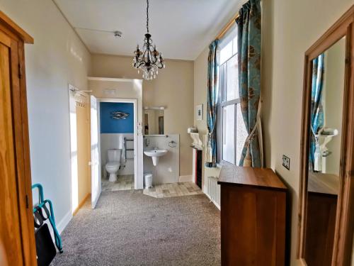 a bathroom with a sink and a toilet and a chandelier at Treventon Guest House in Penzance