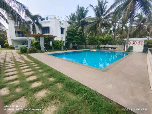 a swimming pool in front of a house at Beach wave villa in Tirupporūr