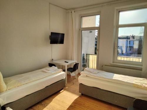 - 2 lits dans une chambre avec une table et une fenêtre dans l'établissement 3-SZ Monteurwohnung am Hansaring, à Neumünster