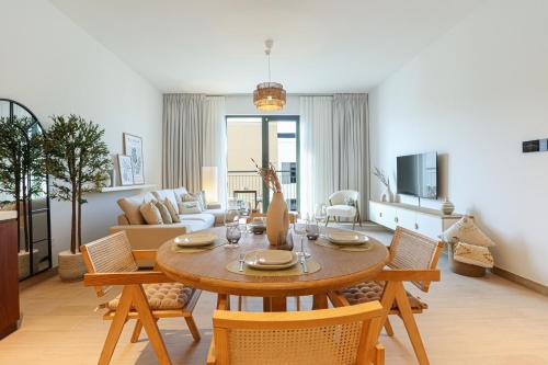 a living room with a wooden table and chairs at HiGuests - Coastal Chic Luxurious Retreat at Port de la Mer in Dubai