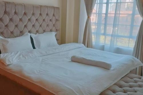 1 dormitorio con cama blanca y ventana grande en Premium 1 Bedroom Ruaka, en Ruaka