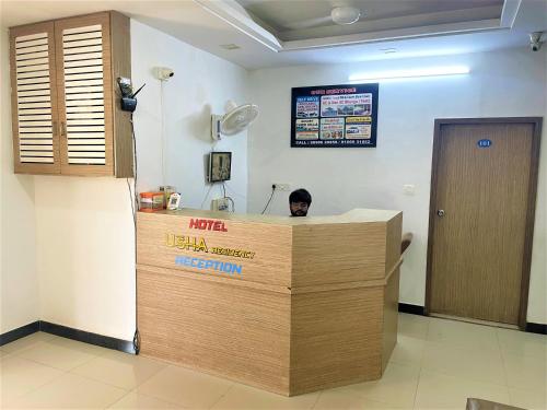 a man sitting at a reception desk in a room at Usha Residency in Bhuj